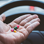 person taking pills inside his car while driving